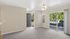 Bright living space with large windows, plush carpet, and private balcony access offering serene outdoor views.