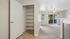 Bright open-concept living area with built-in shelving, large windows, and sliding doors to a lush balcony, perfect for modern living.