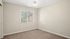 Bright, cozy room with large window, elegant ceiling fixture, and soft carpet flooring.