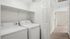 Bright and convenient in-unit laundry space with modern washer and dryer, featuring clean white shelving and ample storage.
