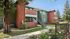 Charming apartment exterior showcasing vibrant green and terracotta hues, with well-maintained landscaping and inviting second-floor balconies.