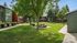 Charming apartment complex surrounded by lush greenery, featuring picnic tables and open grassy areas for relaxation.
