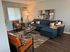 Chic living room with modern d&eacute;cor, featuring a plush blue sectional sofa, stylish leather chairs, and contemporary artwork.