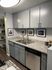 Modern kitchen with sleek grey cabinets, granite countertops, and stainless steel dishwasher, complemented by stylish framed art.