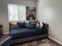 Cozy living space featuring a stylish daybed with plush cushions, modern artwork, and abundant natural light through large window blinds.