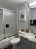 Modern bathroom with sleek granite countertop, elegant shower, and playful cat-themed artwork on the wall.