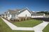 Charming white-painted apartment complex with manicured lawns and attractive pathways under a clear blue sky.