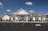 Charming community building with modern white facade and ample parking, set under a clear blue sky.