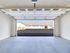 Spacious modern garage with a clean concrete floor, open to a scenic view of an organized parking area and neighboring garages.