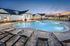 Inviting luxury pool area at sunset with elegant lounge chairs and modern clubhouse in the background.