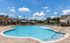 Inviting outdoor pool with crystal-clear water and a sunny, scenic backdrop featuring lounge chairs and umbrellas.