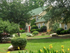 Outdoor colorful landscape with boulders, trees and shrubs, Walkways, Red entrance doors, Beige apartments with white exterior windows.
