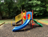 Outdoor Playground Structure: slide, climbers, playhouse, picnic table.