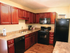 Black appliance package, Neutral colored counter-tops, wood-look laminate flooring, cherry cabinets.