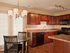 Black appliance package, Neutral colored counter-tops, wood-look laminate flooring, cherry cabinets, chandelier lighting over table and chairs, french doors.
