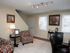 Living room area: Cream colored walls, decorative light fixture, portraits, well lighted windows with shutters, nice furnishings.
