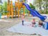 Club Hill Apartments Exterior: colorful playground with slides, and climbing, sand on the ground, 2 children play on a blanket.