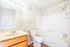 Bright and modern bathroom featuring a large mirror, wooden vanity, and pristine bathtub.