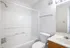 Bright, modern bathroom with a full-size bathtub, toilet, and sleek countertop.