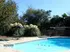 Inviting outdoor pool area surrounded by lush greenery and comfy seating with black umbrellas.