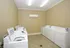 Modern laundry room with multiple top-load washers and dryers, featuring neutral-toned walls and tile flooring.