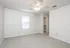 A bright, spacious bedroom with neutral carpet, ceiling fan, and open closet.