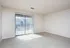 Sunlit empty room with plush carpet and large sliding glass doors leading to a balcony.