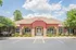 Inviting community clubhouse with stone and wood facade, surrounded by lush greenery.