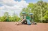 Inviting playground with slides and climbing structures surrounded by lush greenery and open skies.