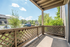 Inviting apartment patio with wooden lattice railing and lush greenery under a clear blue sky.