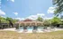 Charming outdoor pool area with sun loungers, nestled in front of a stylish clubhouse surrounded by nature.