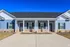Inviting exterior of a modern duplex with blue siding and white trim, featuring a shared entryway and manicured lawn.