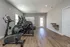 Bright gym room with modern exercise equipment and wooden flooring.