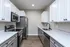 Contemporary kitchen with white cabinets, stainless steel appliances, and hardwood flooring.
