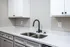 Modern kitchen sink with elegant white cabinets and speckled countertop.
