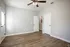 Spacious bedroom with sleek wood flooring and natural light, featuring a ceiling fan.