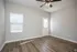 Spacious room with elegant wood flooring, gray walls, ceiling fan, and ample natural light.