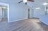 Bright and spacious living area with elegant wood flooring, ceiling fan, and modern light fixture, seamlessly connected to a sleek kitchen with a granite countertop.