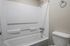 Modern bathroom featuring a pristine white bathtub with a showerhead, sleek fixtures, and convenient towel holder.