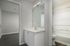 Modern bathroom with sleek white vanity, large mirror, and bright lighting, featuring an inviting bathtub and stylish flooring.