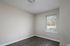 Bright, cozy room with sleek hardwood floors and a large window providing natural light; perfect for a home office or reading nook.