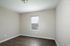 Bright and cozy bedroom with modern gray walls, sleek dark flooring, and a single window providing natural light.