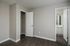 Bright, modern bedroom with sleek hardwood floors and neutral walls, featuring an open walk-in closet and a glimpse of the bathroom.