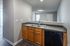 Modern kitchen area with sleek countertops, dual sink, and elegant wood cabinetry, adjacent to a spacious open-concept living space.