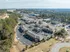 Aerial view of a charming apartment complex in a lush, serene neighborhood, surrounded by greenery and conveniently located near shopping centers.