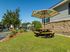 Inviting outdoor area with a vibrant striped umbrella shading a wooden picnic table, surrounded by lush greenery and colorful flowers, showcasing community living.