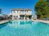 Charming two-story home with inviting pool, perfect for relaxation and entertaining against a clear blue sky.