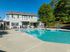 Inviting apartment exterior with sparkling swimming pool, surrounded by lush greenery, perfect for relaxation and leisure.