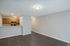 Modern open-concept apartment featuring sleek hardwood floors, a cozy kitchen with wooden cabinetry, and bright lighting.