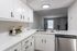 Modern kitchen with sleek white cabinets, stainless steel dishwasher, and an elegant black faucet, offering a cozy and inviting ambiance.